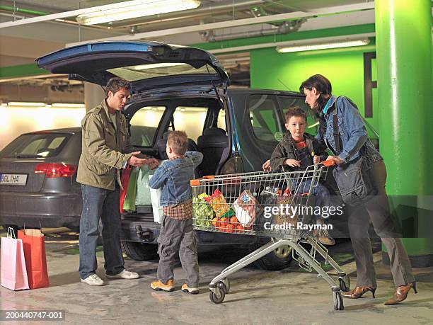 parents and two sons (4-6) loading shopping into car in car park - open day 6 fotografías e imágenes de stock