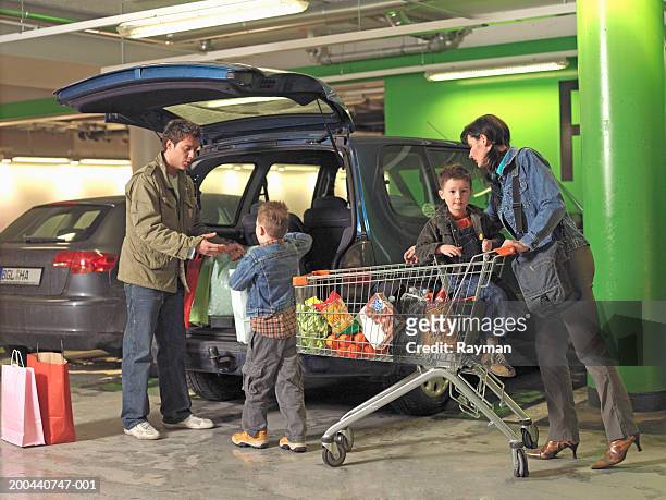 parents and two sons (4-6) loading shopping into car in car park - open day 5 stockfoto's en -beelden