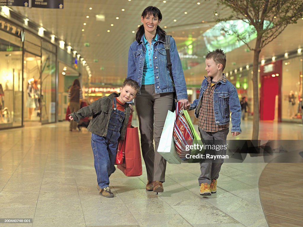 Mother walking with two sons (4-6) in shopping centre, smiling