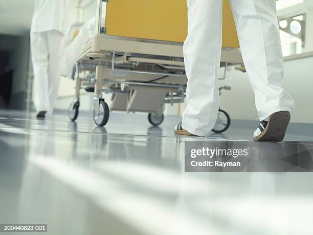 two nurses wheeling hospital bed through corridor, low section - hospital bed stockfoto's en -beelden