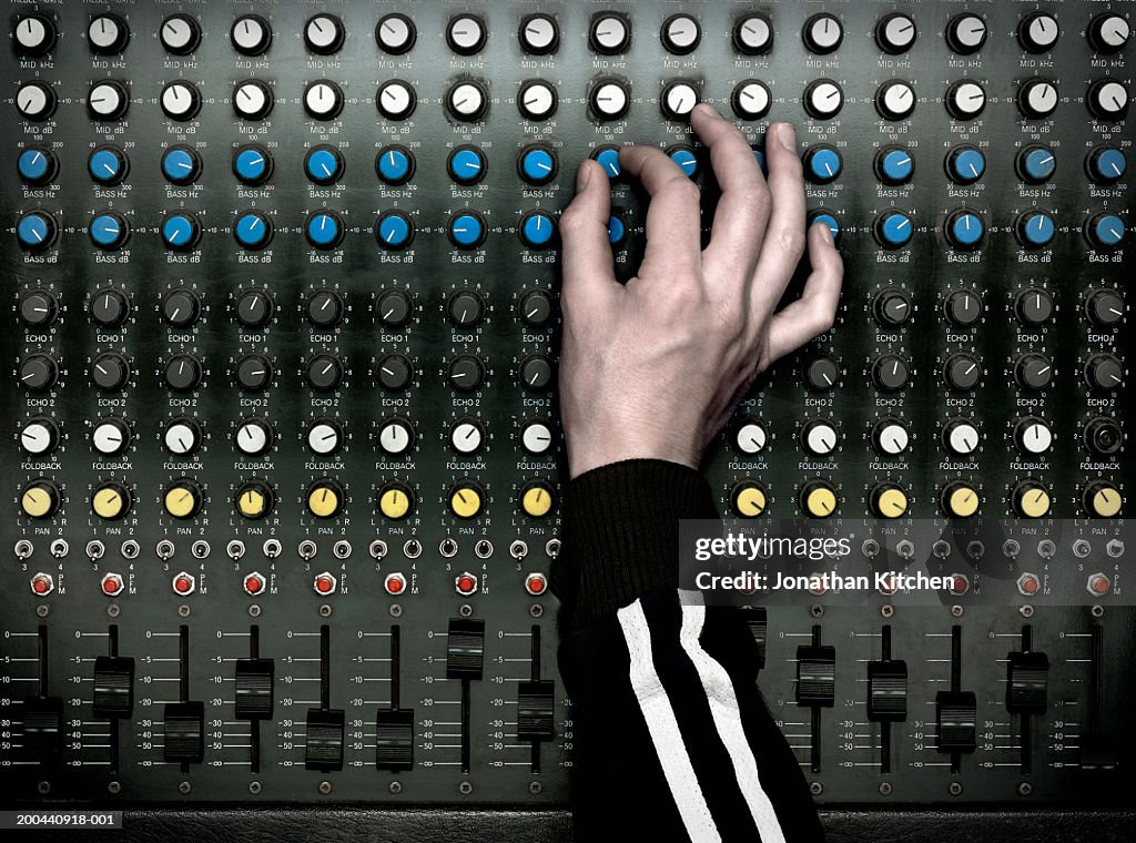 Sound technician adjusting dial on mixing desk, close-up