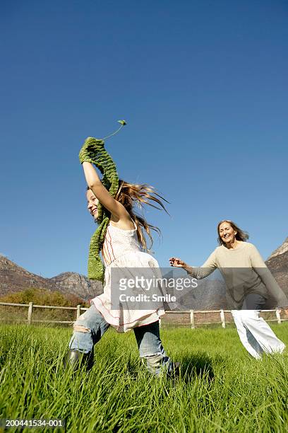 grandmother and granddaughter (8-10) running in field - smile woman child stockfoto's en -beelden
