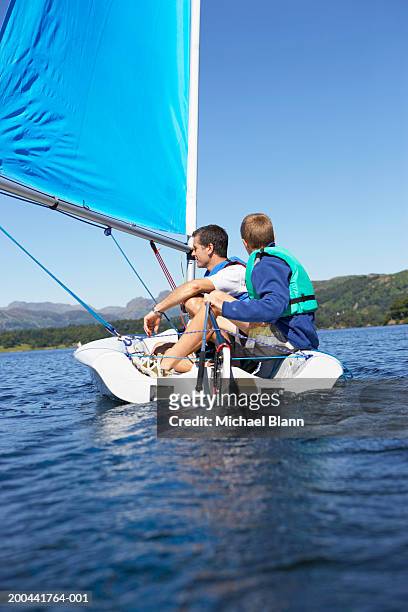 father and son (11-13) sailing in dinghy on lake - kid sailing imagens e fotografias de stock
