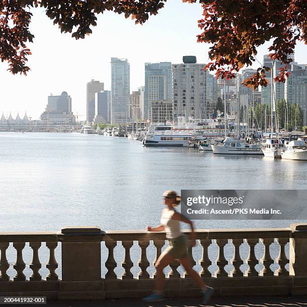 mature woman jogging along waterfront, sunrise (blurred motion) - vancouver people stock pictures, royalty-free photos & images