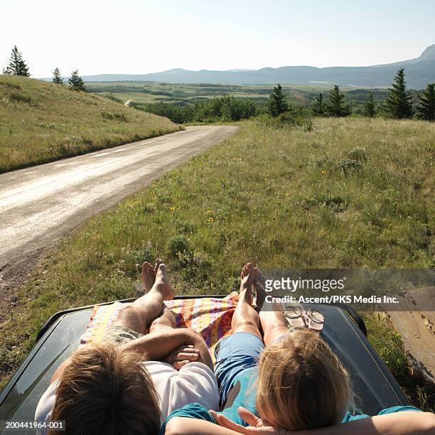 couple sunning on hood of car, rear view, sunrise - lying on back ストックフォトと画像