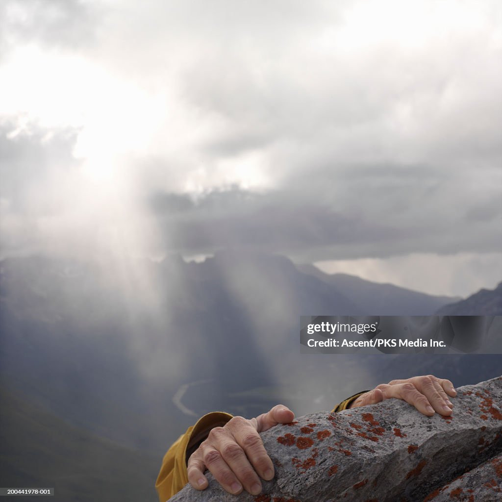 Female climber gripping slab of lichened limestone, close-up, sunset