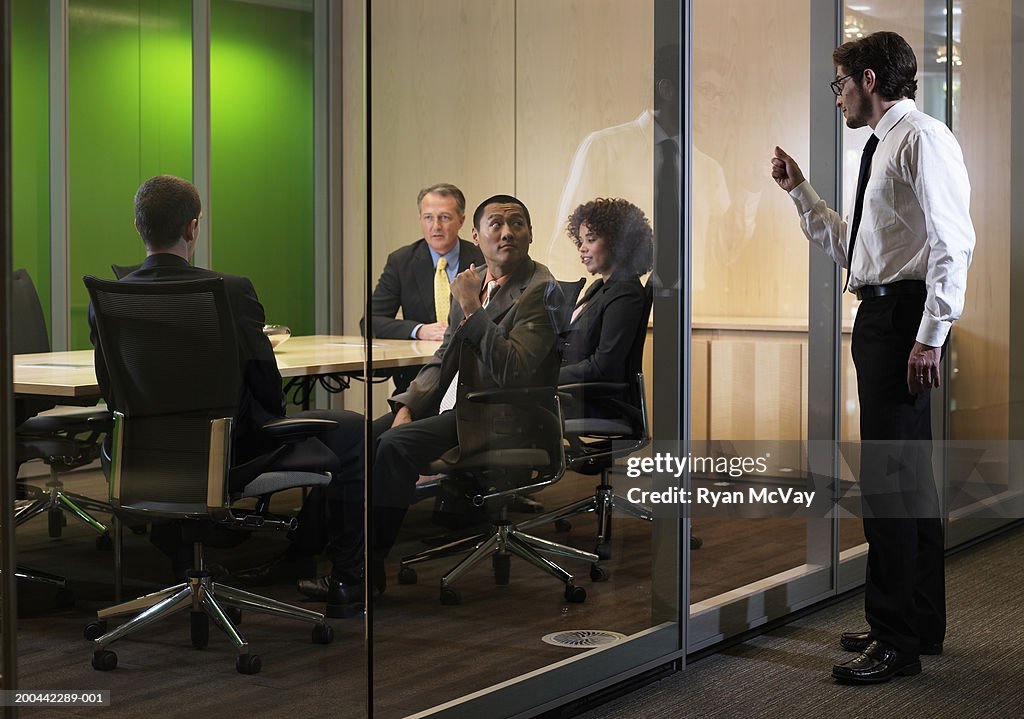 Business executives in meeting, man interrupting with knock on glass