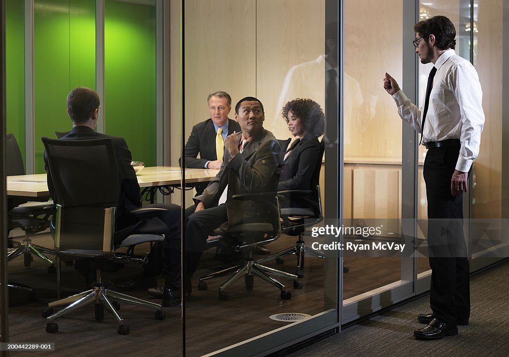 Business executives in meeting, man interrupting  with knock on glass