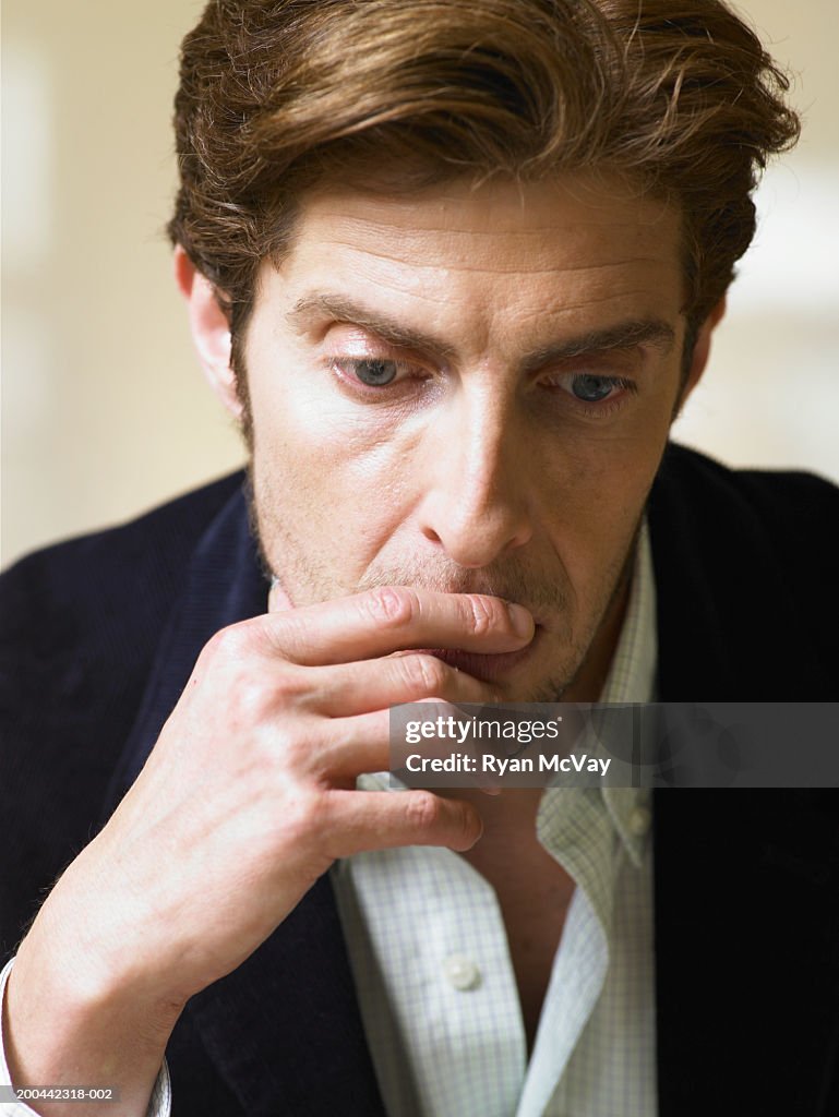 Man in white shirt and jacket looking pensive
