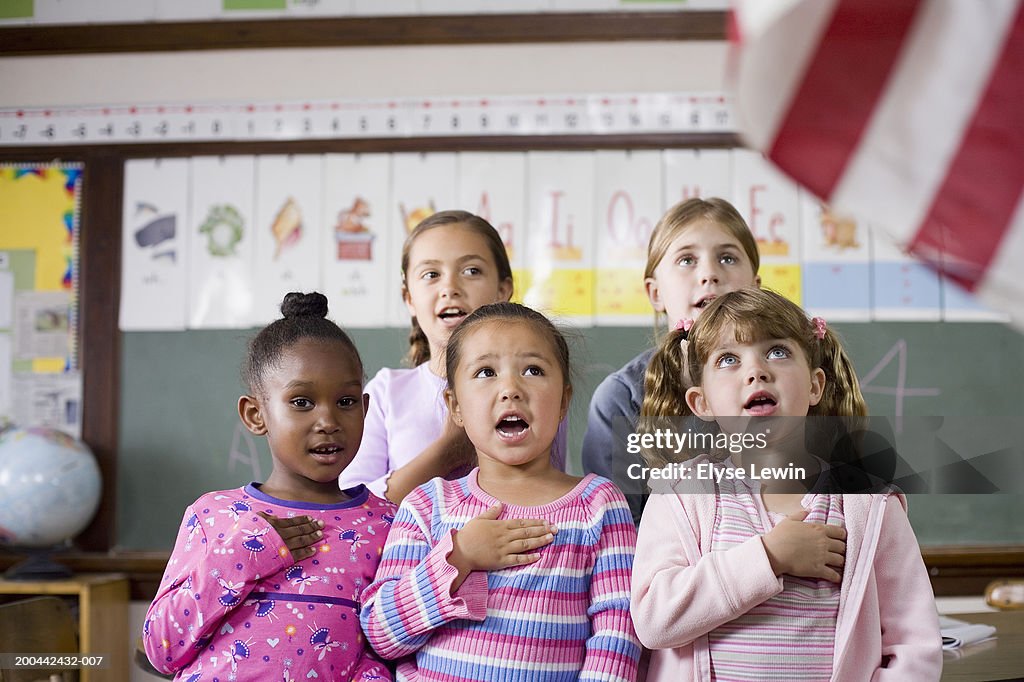 Girls (6-12) singing with hands on chests, close-up