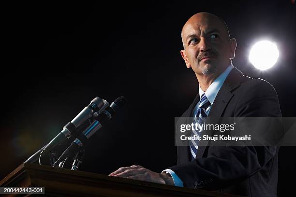 mature man standing at podium, low angle view - politician speaking stock pictures, royalty-free photos & images