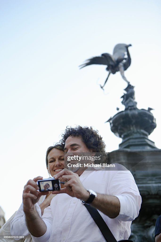 England, London, Piccadilly Circus, couple using camera, smiling