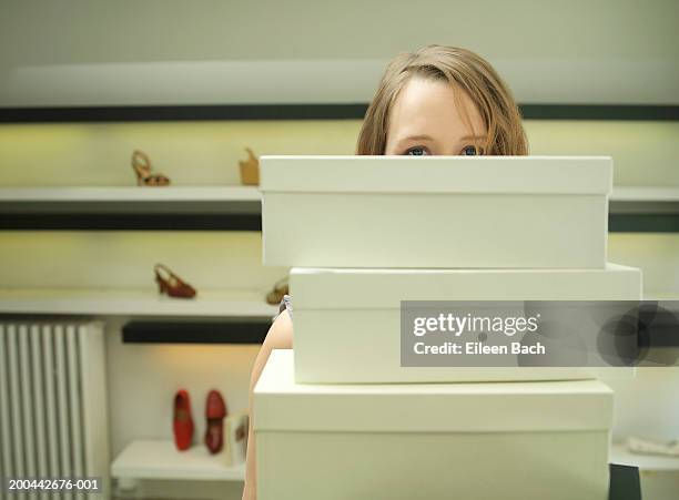 young woman holding stack of shoe boxes in shop, portrait - shoe boxes stock pictures, royalty-free photos & images