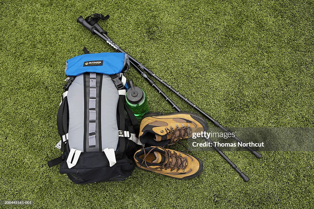 Backpack, hiking boots, water bottle and hiking pole on turf