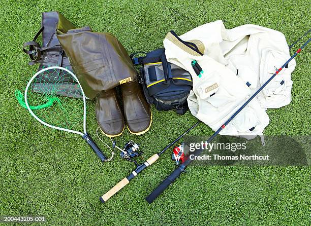 fishing poles, net, creel, fishing vest and wading boots on turf - fishing tackle stock pictures, royalty-free photos & images