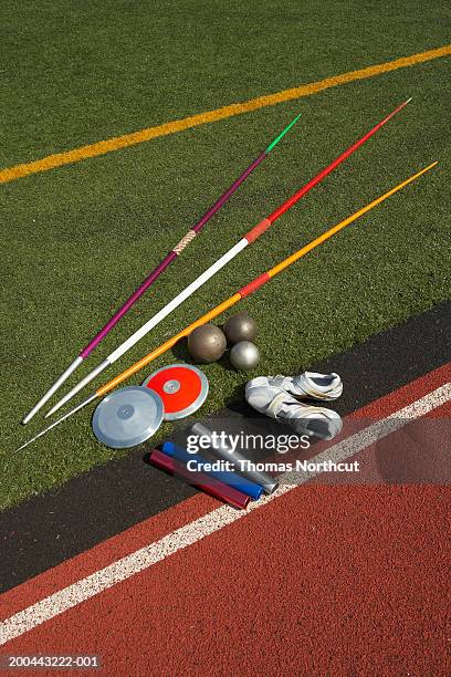 javelins, discuses, relay batons, shots and sports shoes beside track - track and field baton stock pictures, royalty-free photos & images