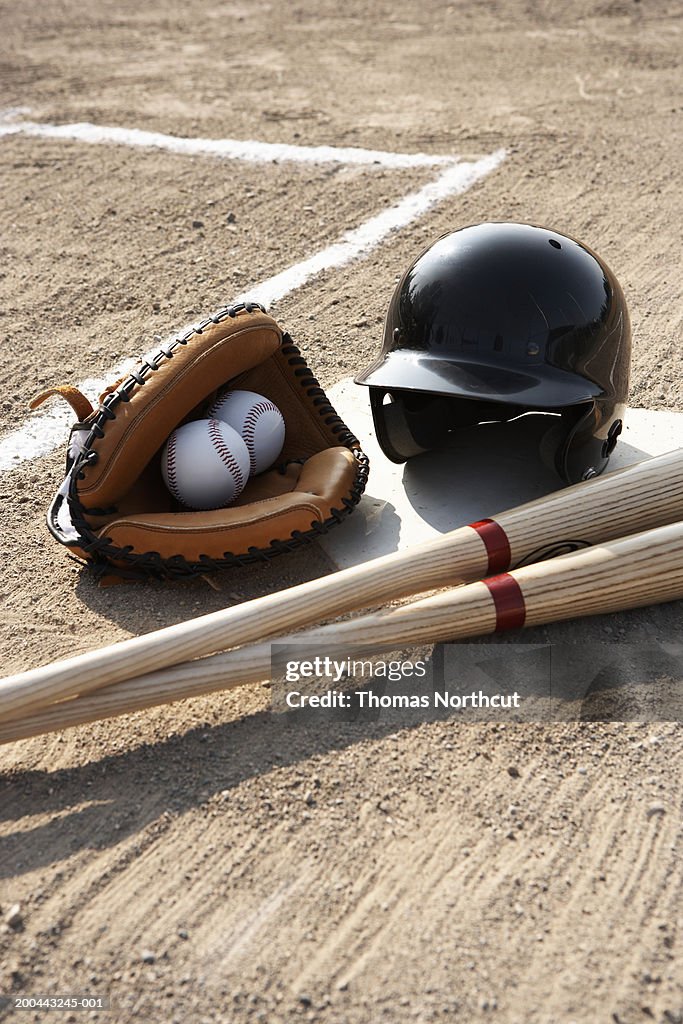 Baseball glove, balls, bats and baseball helmet at home plate