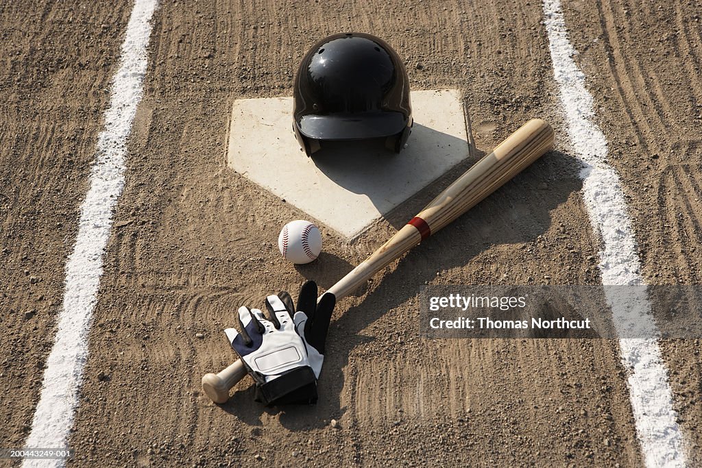 Baseball, bat, batting gloves and baseball helmet at home plate