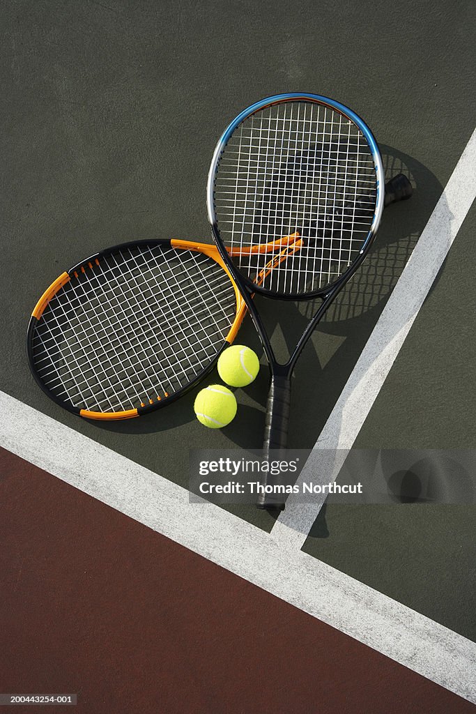 Two tennis rackets and tennis balls on tennis court, overhead view