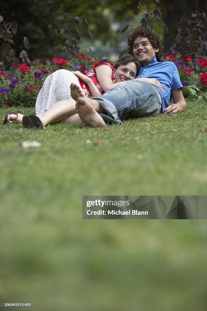 Young couple relaxing on grass in park, smiling, ground view