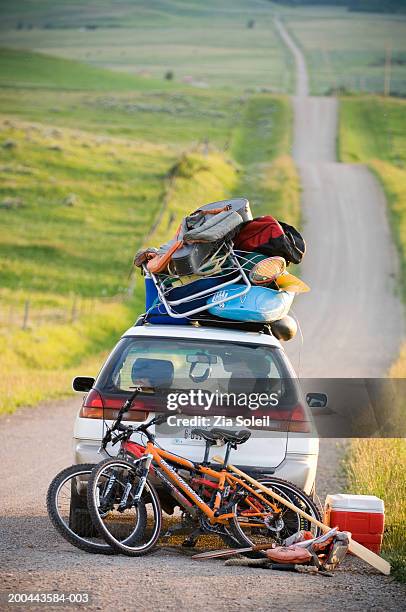 car loaded with vacation gear on empty road - voll geladen stock-fotos und bilder