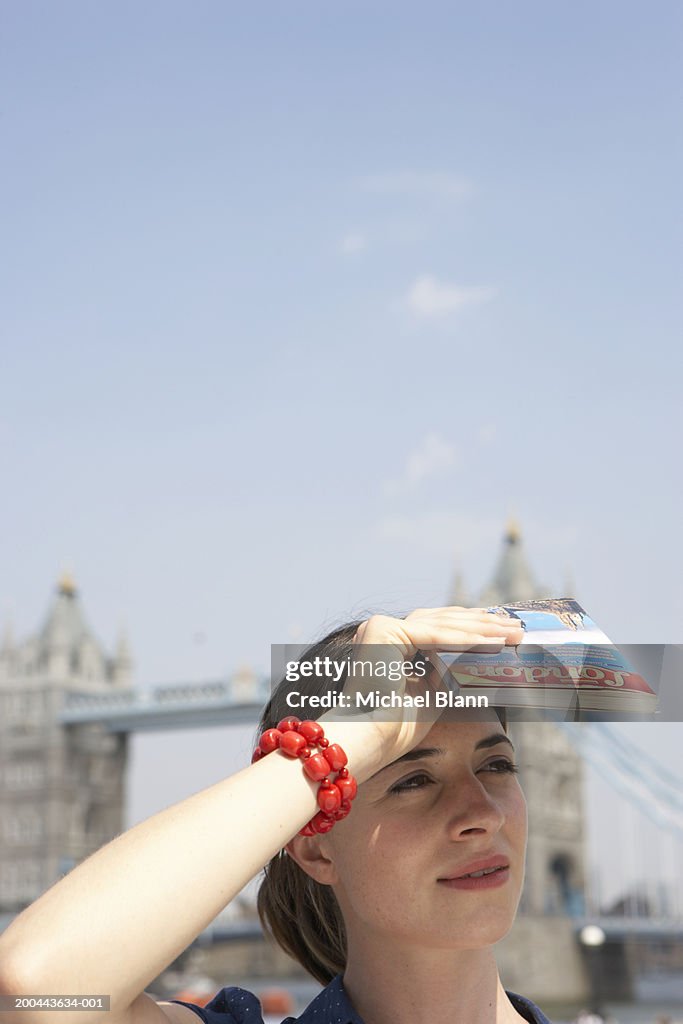 England, London, woman shielding eyes from sun, close-up