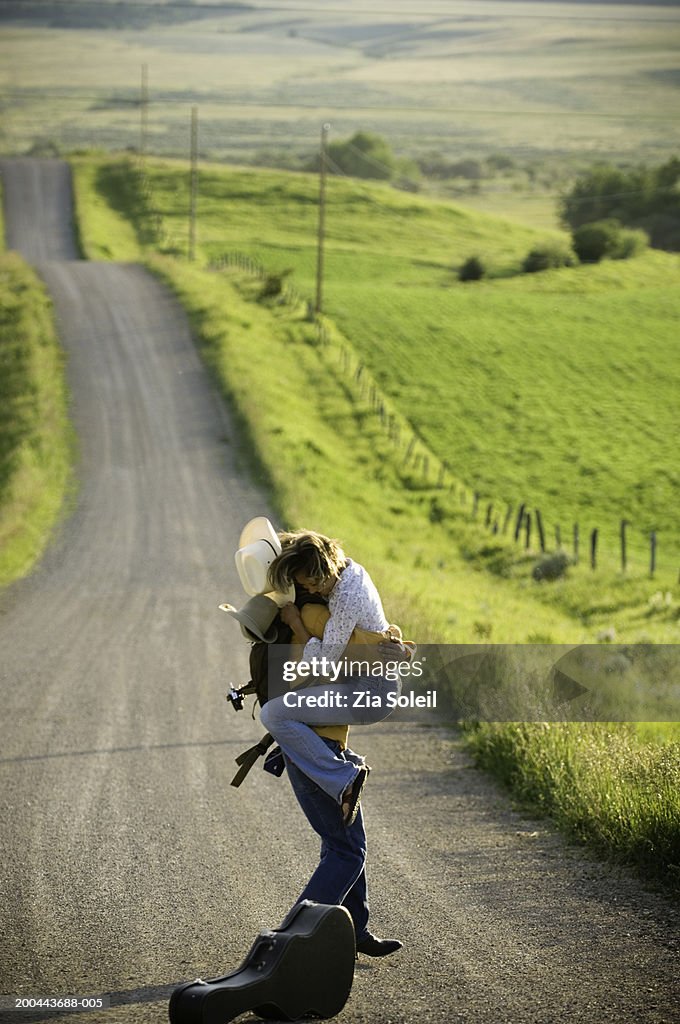 Young couple embracing on rural road, side view