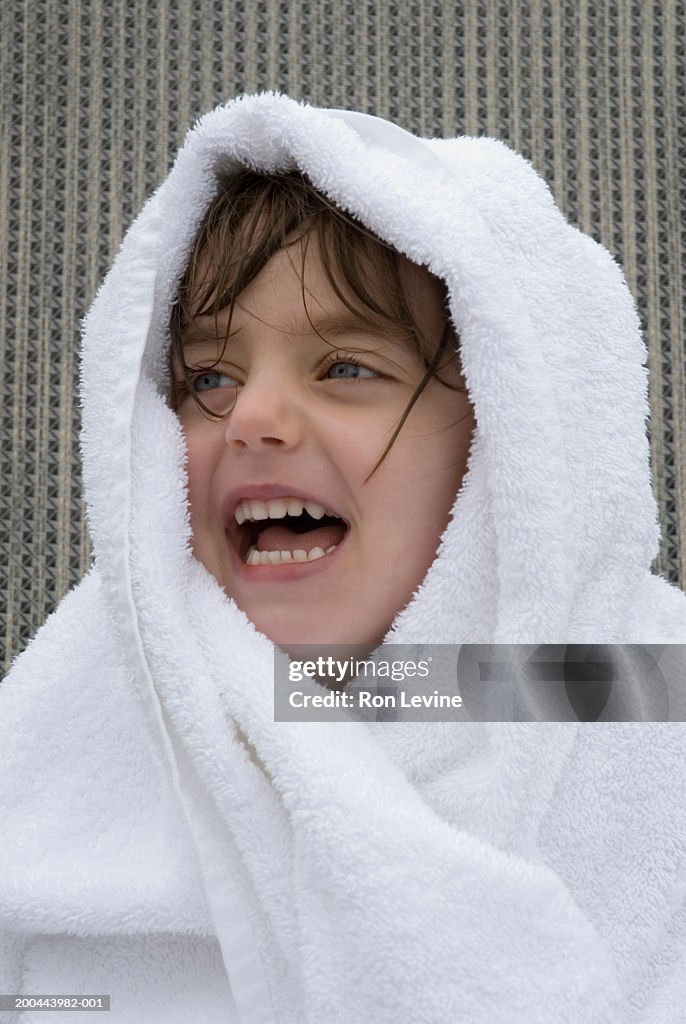 Girl (2-4) wrapped in towel, laughing, close-up