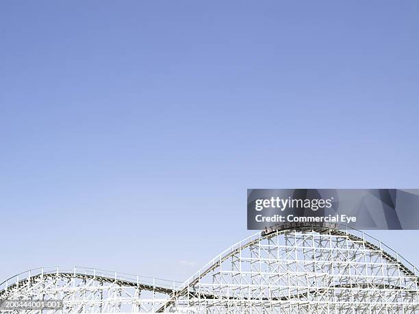 rollercoaster with people raising arms in air in cars on top - rollercoaster stock pictures, royalty-free photos & images