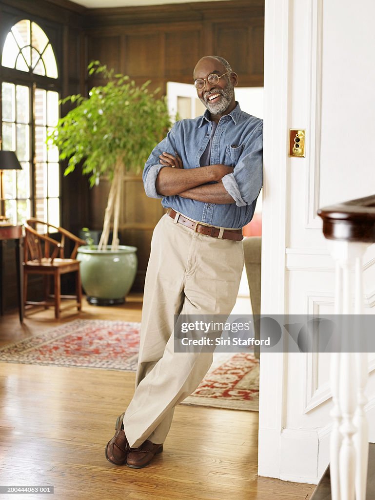 Mature man leaning on wall post in house