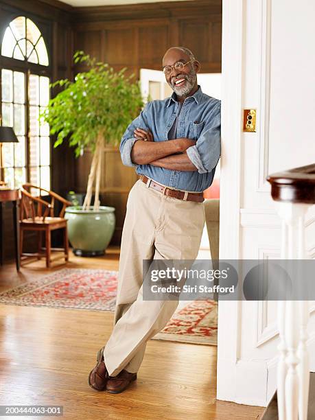 mature man leaning on wall post in house - solo uomini maturi foto e immagini stock