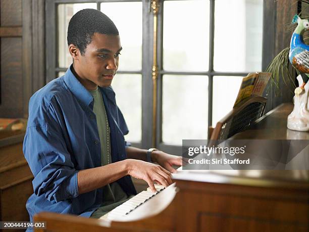 young man playing piano in house - pianist stockfoto's en -beelden