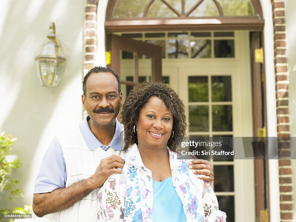 Mature couple standing in front of home