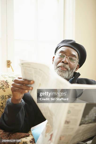 mature man reading newspaper on sofa - reading newspaper stock pictures, royalty-free photos & images