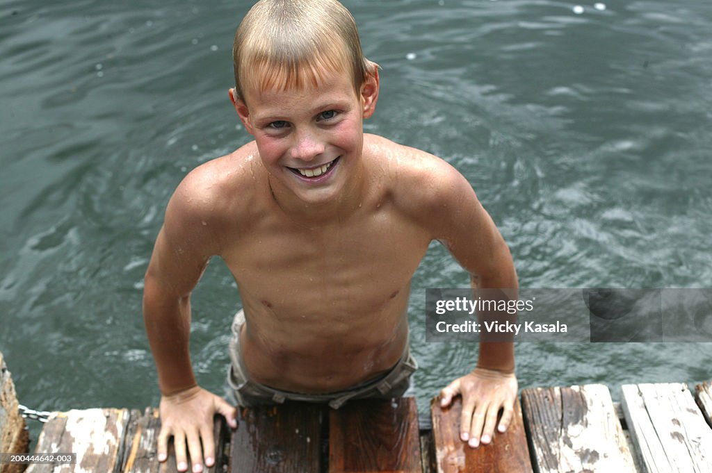 Portrait of boy (11-13) leaning on edge of pier, smiling