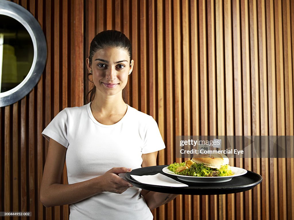 Waitress holding tray with burger, portrait