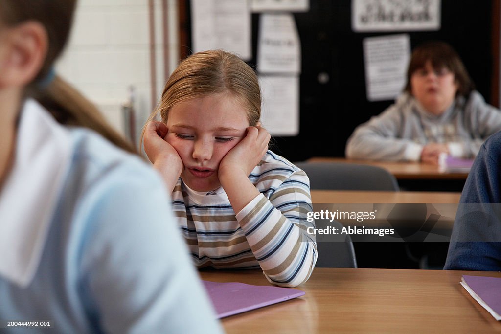 Schoolchildren (7-11) in classroom, girl resting face in hands