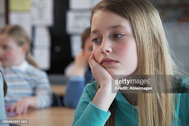 schoolgirl (7-11) in classroom, resting face in hand, close-up - school close up stock-fotos und bilder