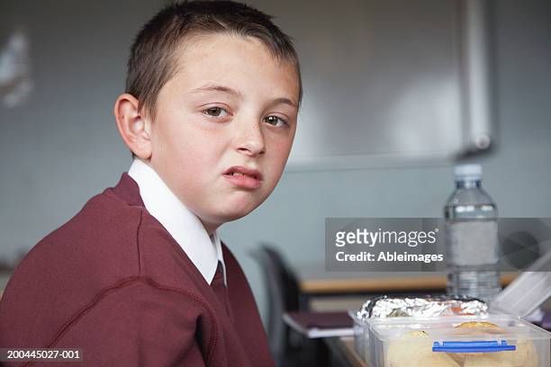 schoolboy (8-10) desk, packed lunch on table, portrait - disgusto foto e immagini stock