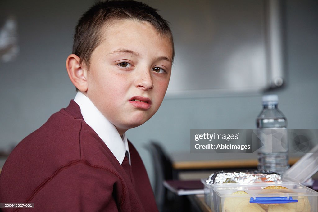 Schoolboy (8-10) desk, packed lunch on table, portrait