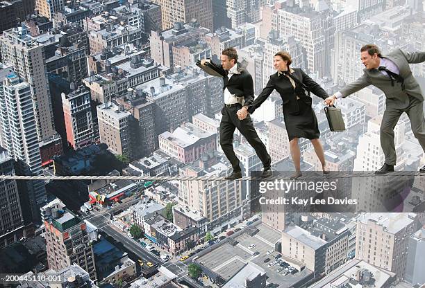 windswept businessman and woman on tightrope over cityscape - woman tightrope stock pictures, royalty-free photos & images