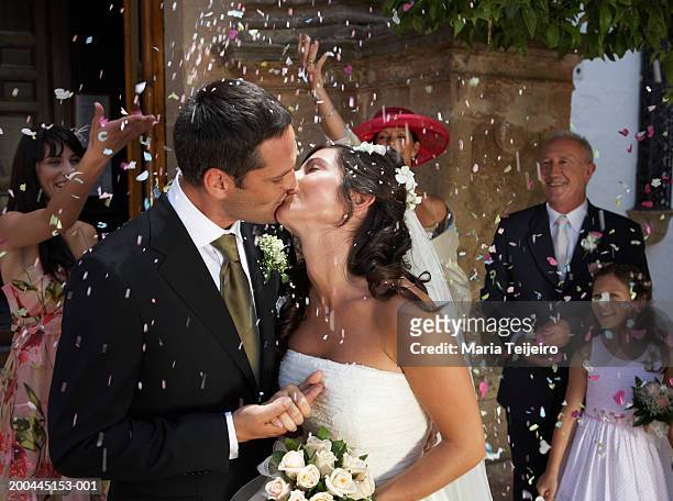 guests throwing confetti over kissing bride and groom, outdoors - maria weding stock pictures, royalty-free photos & images