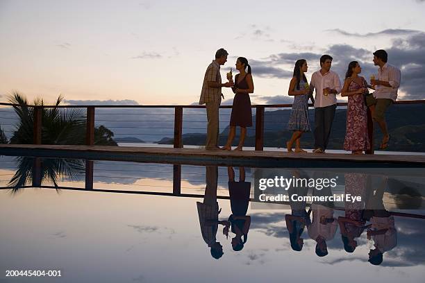 couples having cocktails beside pool, sunset - cocktail dress stock-fotos und bilder