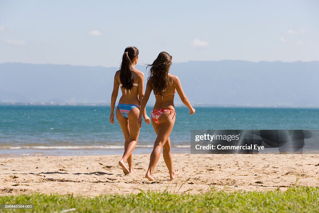 Two Young Women Walking On Beach Rear View High-Res Stock Photo