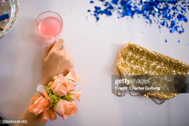 young woman drinking juice at prom, close-up (focus on wrist corsage) - gold purse stock-fotos und bilder