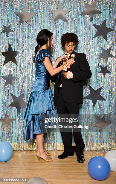 teenage girl (16-18) in formal dress adjusting young man's boutonniere - proms stock pictures, royalty-free photos & images