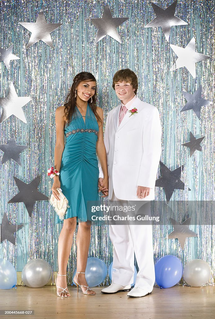 Teenage boy and girl (14-16) in formalwear holding hands, portrait