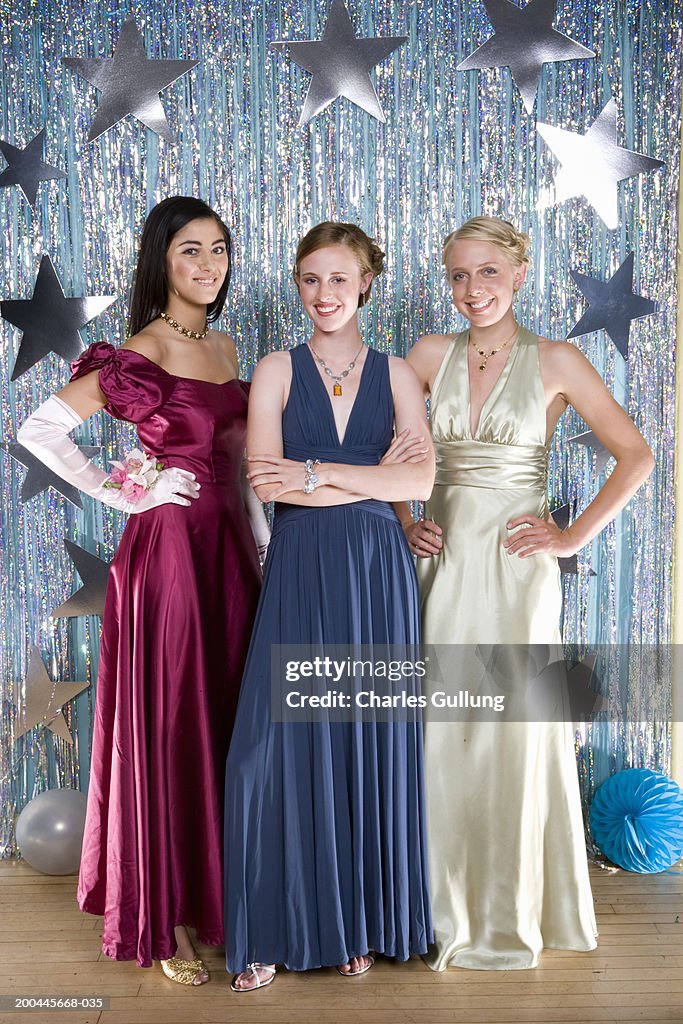 Three teenage girls (16-18) wearing formal dresses, smiling, portrait