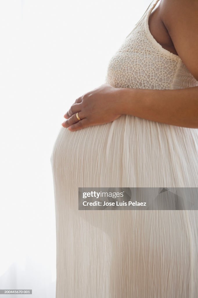 Pregnant woman touching abdomen, side view, close-up