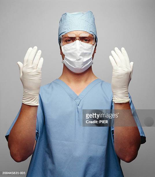 male surgeon wearing scrubs, holding up gloved hands, portrait - surgical glove stock pictures, royalty-free photos & images